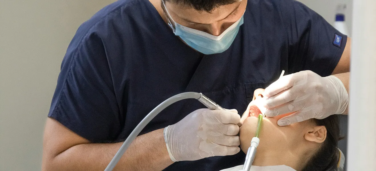 Doktor gigi membersihkan gigi pesakit